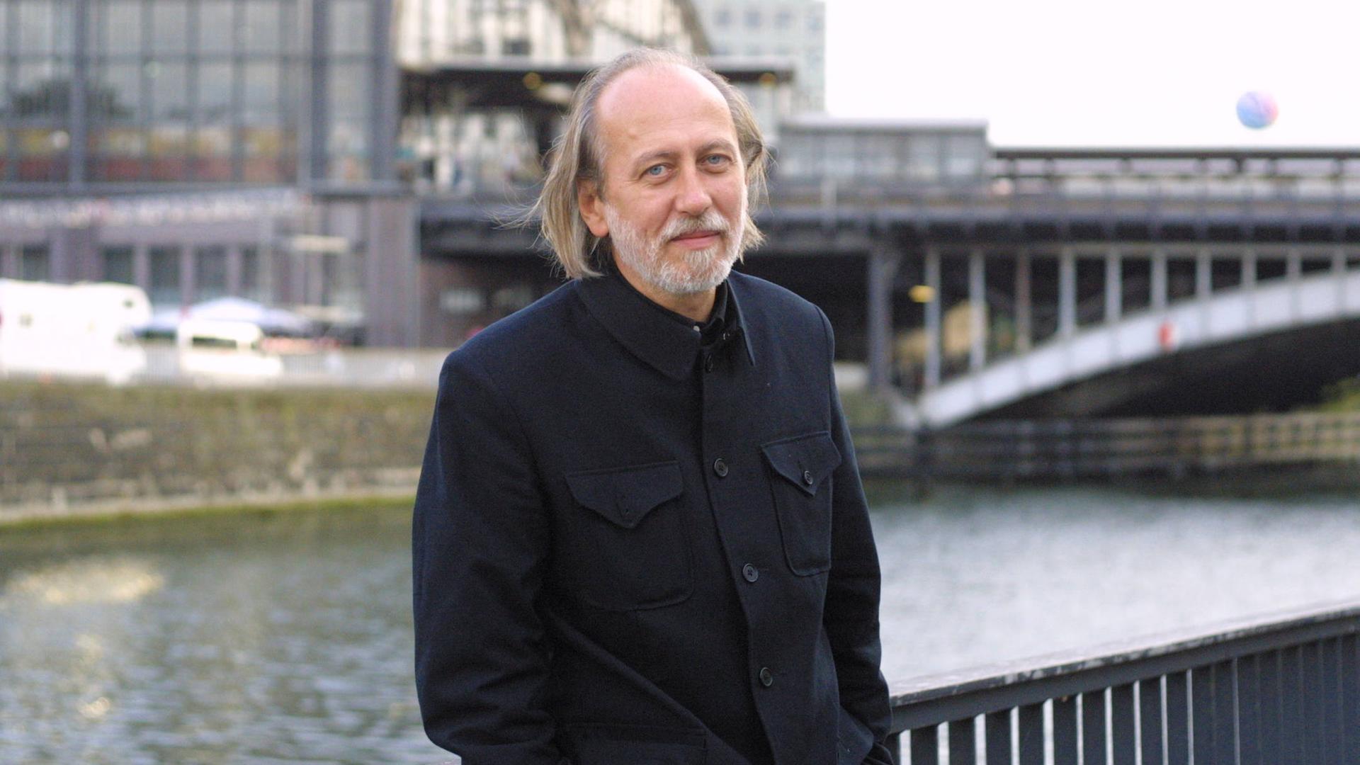 Der Autor László Krasznahorkai steht vor der Spree in Berlin 