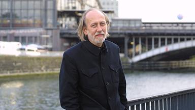 Der Autor László Krasznahorkai steht vor der Spree in Berlin 