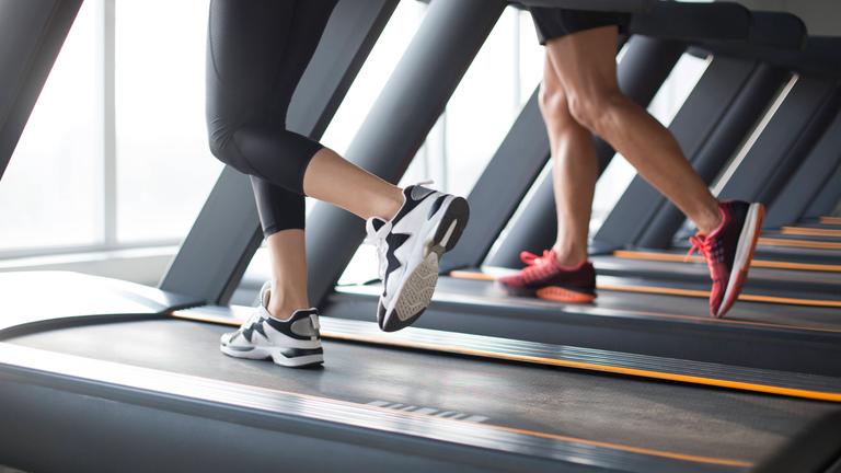 Mann und Frau auf zwei Laufbändern im Fitnessstudio
