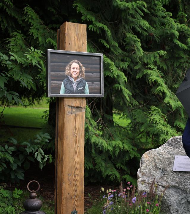 Menschen stehen an einer Gedenkstätte im Kurpark Partenkirchen vor einem Portrait der ehemaligen Biathletin Laura Dahlmeier.
