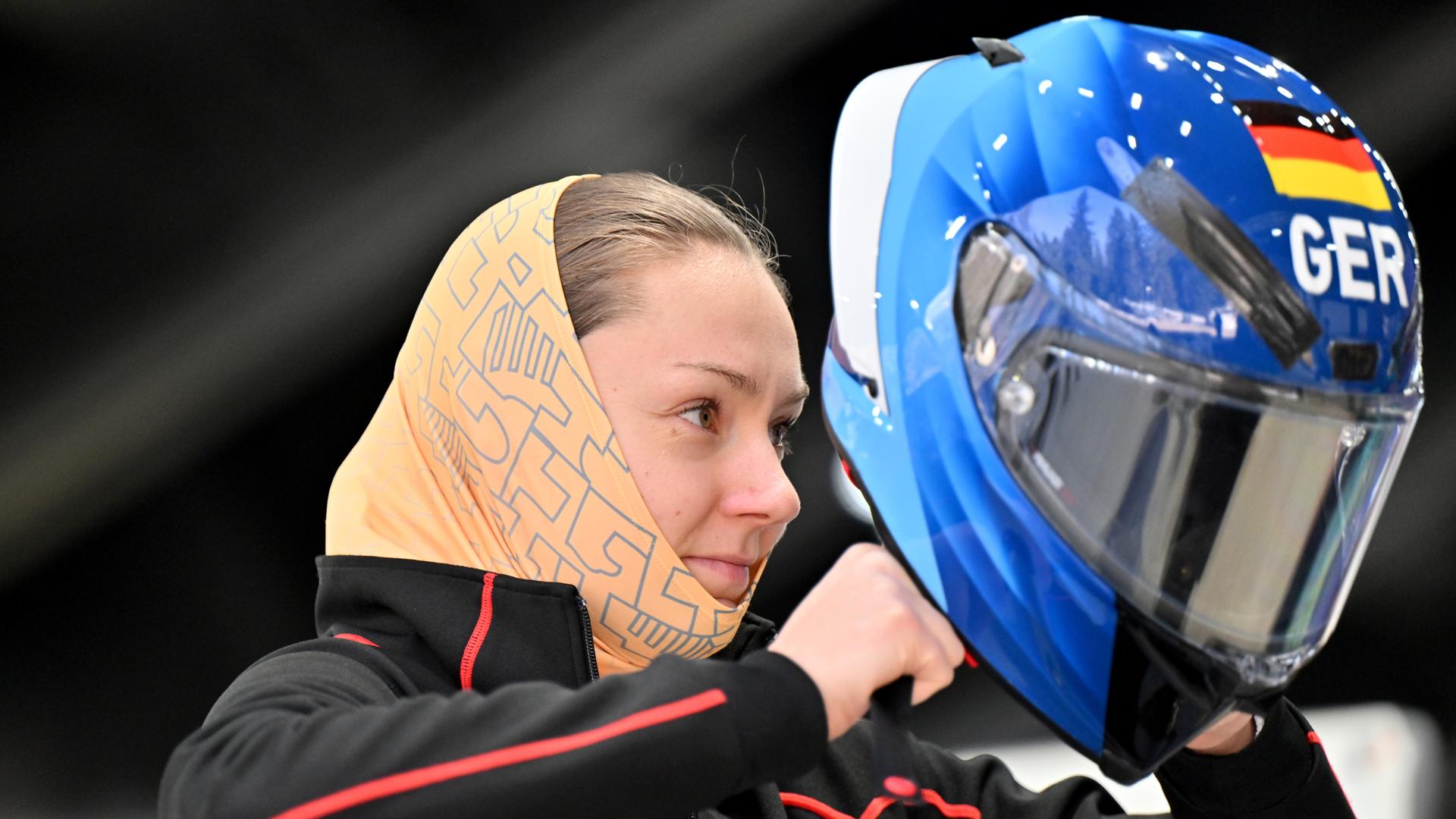 Laura Nolte zieht sich vor dem Monobob-Training in Cortina den Helm an.