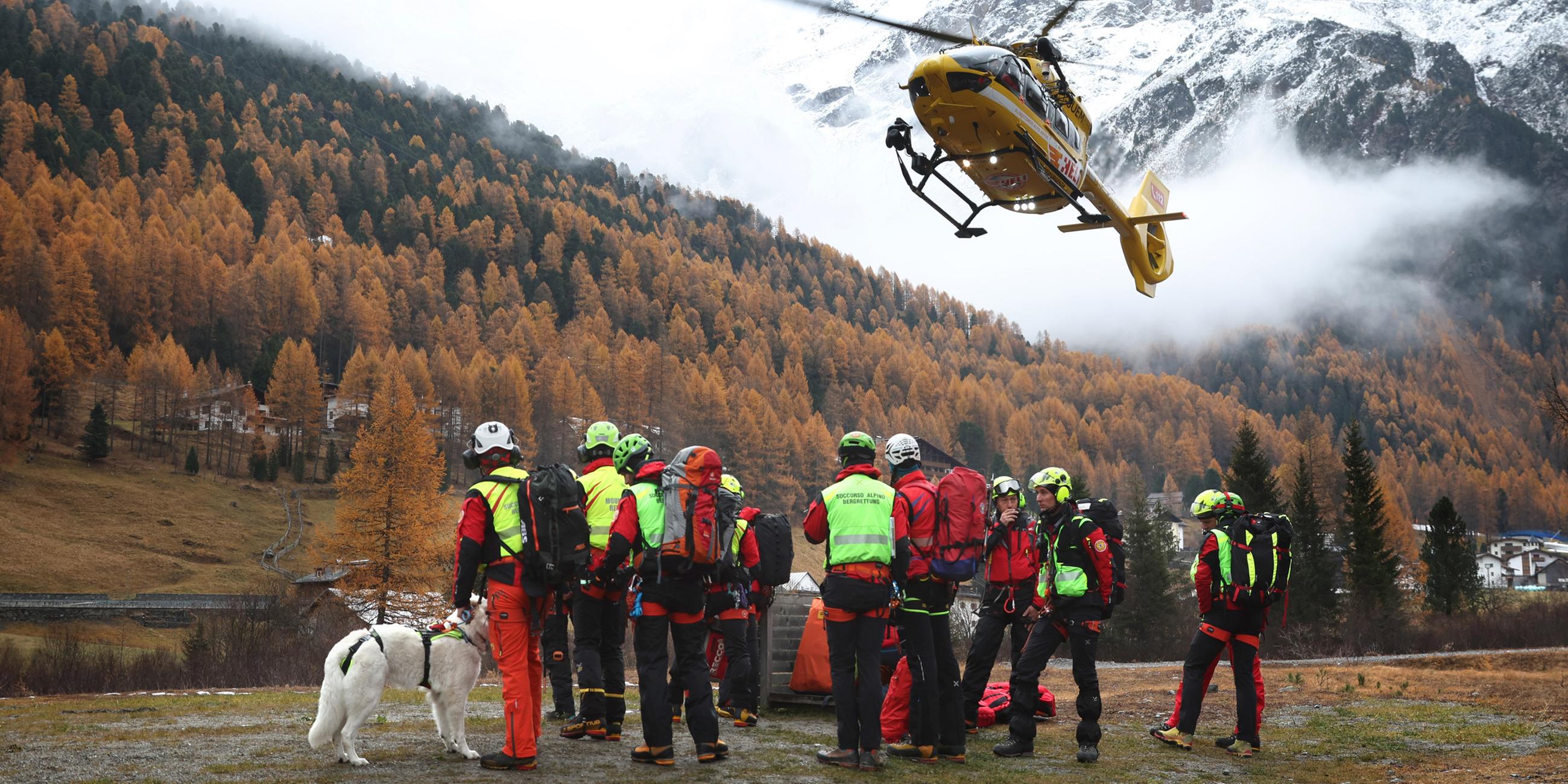  Ein Hubschrauber der Bergrettung landet vor Bergrettern. Nach dem Tod von mindestens drei deutschen Bergsteigern bei einem Lawinenunglück am 02.11.2025 in Südtirol ist die Suche nach zwei Vermissten wieder aufgenommen worden.