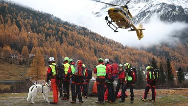  Ein Hubschrauber der Bergrettung landet vor Bergrettern. Nach dem Tod von mindestens drei deutschen Bergsteigern bei einem Lawinenunglück am 02.11.2025 in Südtirol ist die Suche nach zwei Vermissten wieder aufgenommen worden.