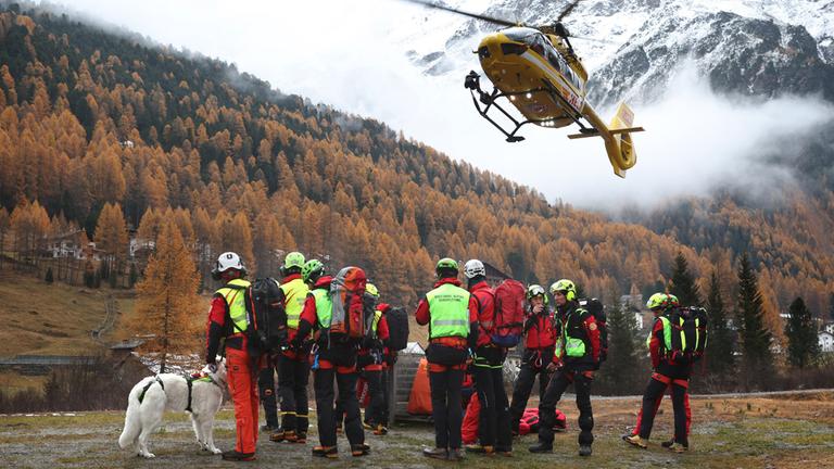  Ein Hubschrauber der Bergrettung landet vor Bergrettern. Nach dem Tod von mindestens drei deutschen Bergsteigern bei einem Lawinenunglück am 02.11.2025 in Südtirol ist die Suche nach zwei Vermissten wieder aufgenommen worden.