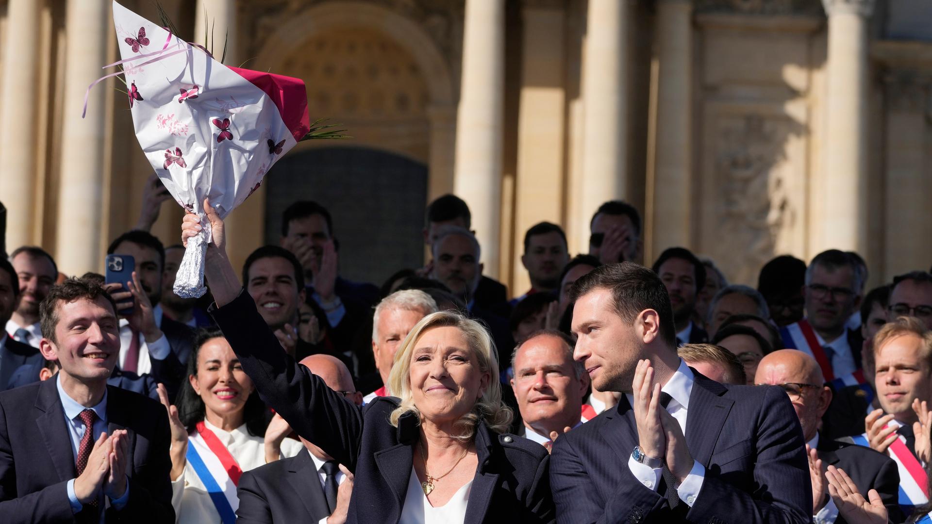 French far-right leader Marine Le Pen, left, smiles with Jordan Bardella during the French far-right party national rally near the parliament in Paris