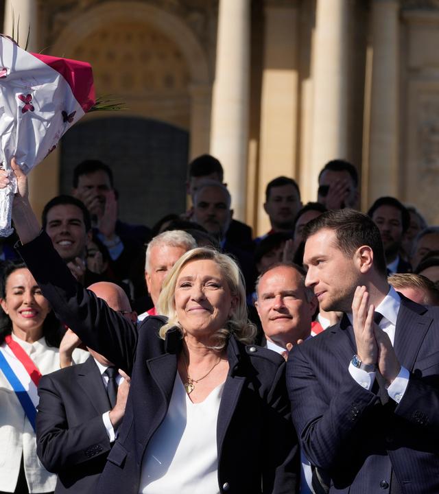 French far-right leader Marine Le Pen, left, smiles with Jordan Bardella during the French far-right party national rally near the parliament in Paris