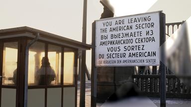 Zu sehen ist ein Grenzübergang mit Wachhaus und einem Hinweisschild zum verlassen des amerikanischen Sektors. 