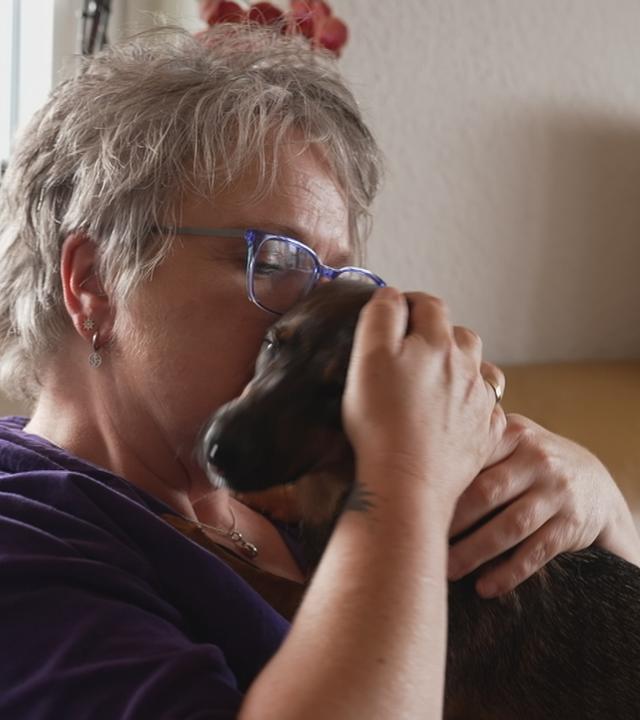 Frau nach einer Krebserkrankung kuschelt mit ihrem Hund.