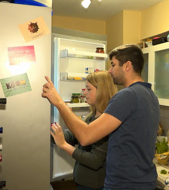 Frau und Mann schauen in den Kühlschrank