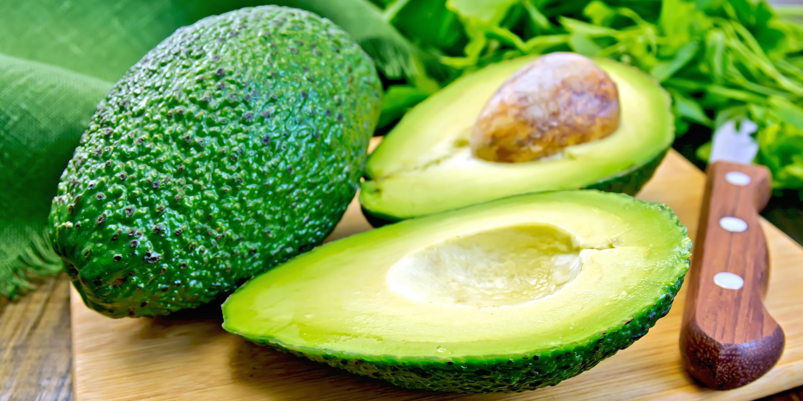 Eine ganze Avocado und eine angeschnitte Avocado