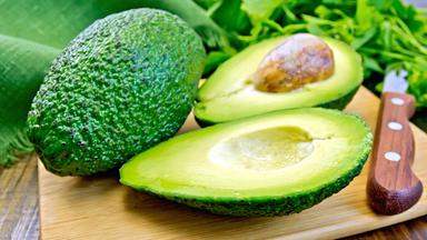 Eine ganze Avocado und eine angeschnitte Avocado
