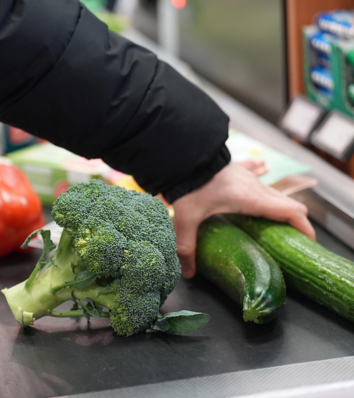 Ein Mann legt seinen Einkauf auf das Laufband an einer Kasse in einem Supermarkt.