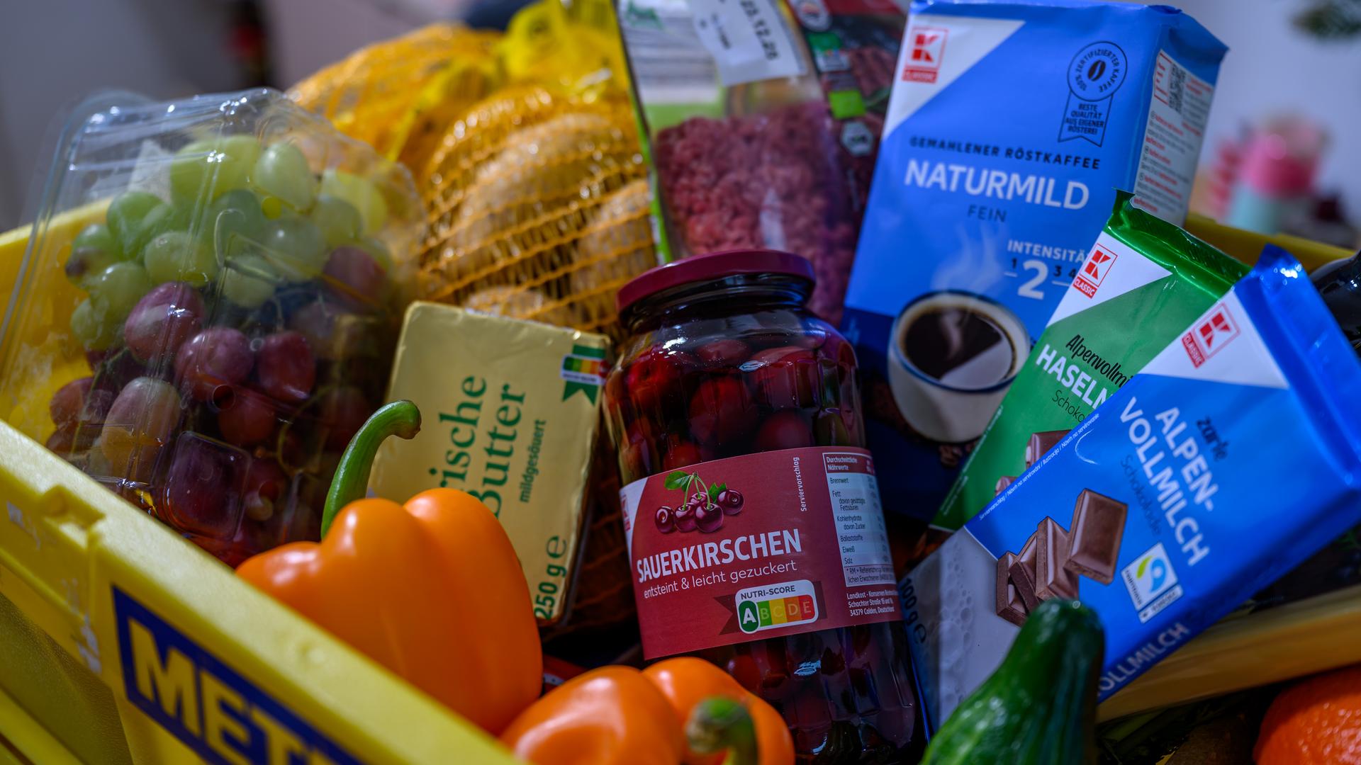 Ein Kiste mit Lebensmitteln, deren Preise sich im Jahr 2025 stark verändert haben. Zu sehen sind etwa Weintrauben, Butter und Sauerkirschen.