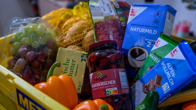 Ein Kiste mit Lebensmitteln, deren Preise sich im Jahr 2025 stark verändert haben. Zu sehen sind etwa Weintrauben, Butter und Sauerkirschen.