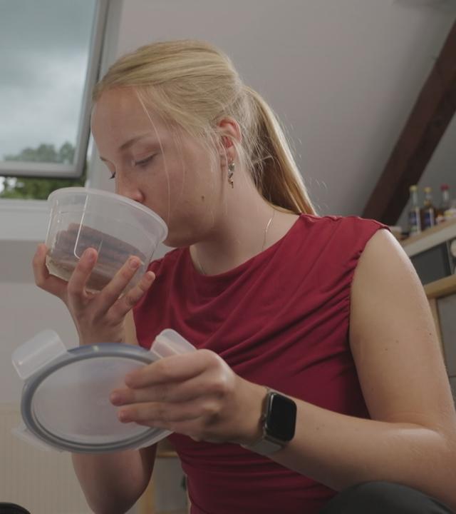 Frau riecht an Lebensmittel in einer Dose, um zu prüfen, ob sie das Essen sicher gelagert hat.