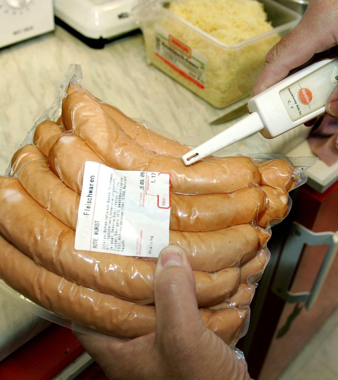 Lebensmittelkontrolleur misst die Temperatur von eingeschweißten Würsten