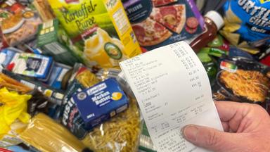 Lebensmittel in einem Einkaufswagen - Hand hält Kassenbon