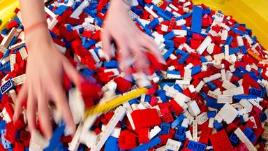 Kinderhände kramen in einem Haufen von Legosteienen.