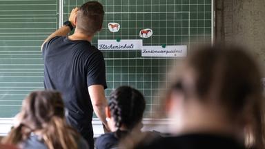 Ein Lehrer macht im Unterricht einer vierten Klasse einer Grundschule einen Tafelanschrieb, während an der Tafel Zettel mit der Aufschrift «Flächeninhalt» und «Zentimeterquadrat» hängen