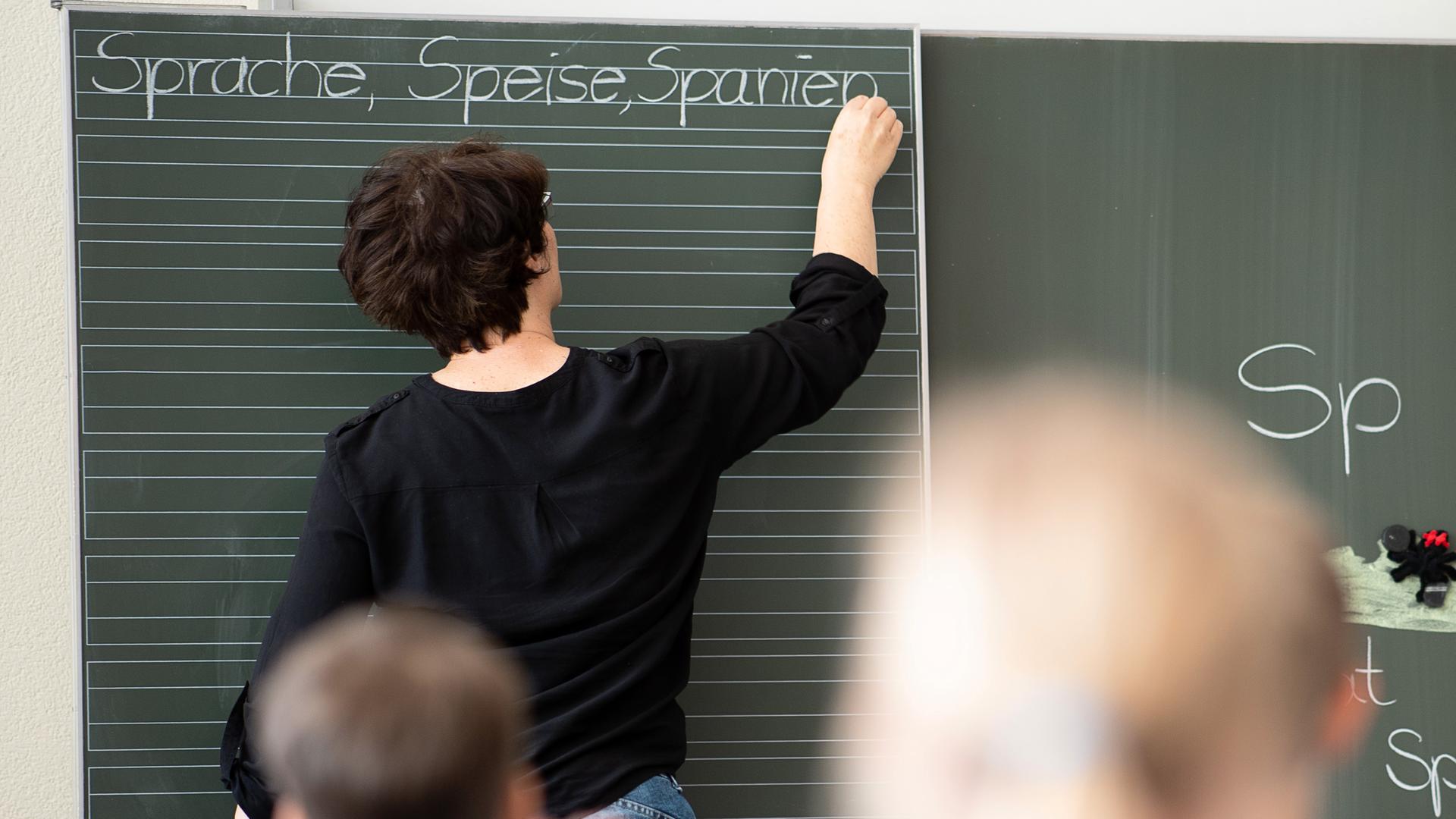 Archiv: Eine Lehrerin schreibt in einer Schule Worte an eine Tafel. 