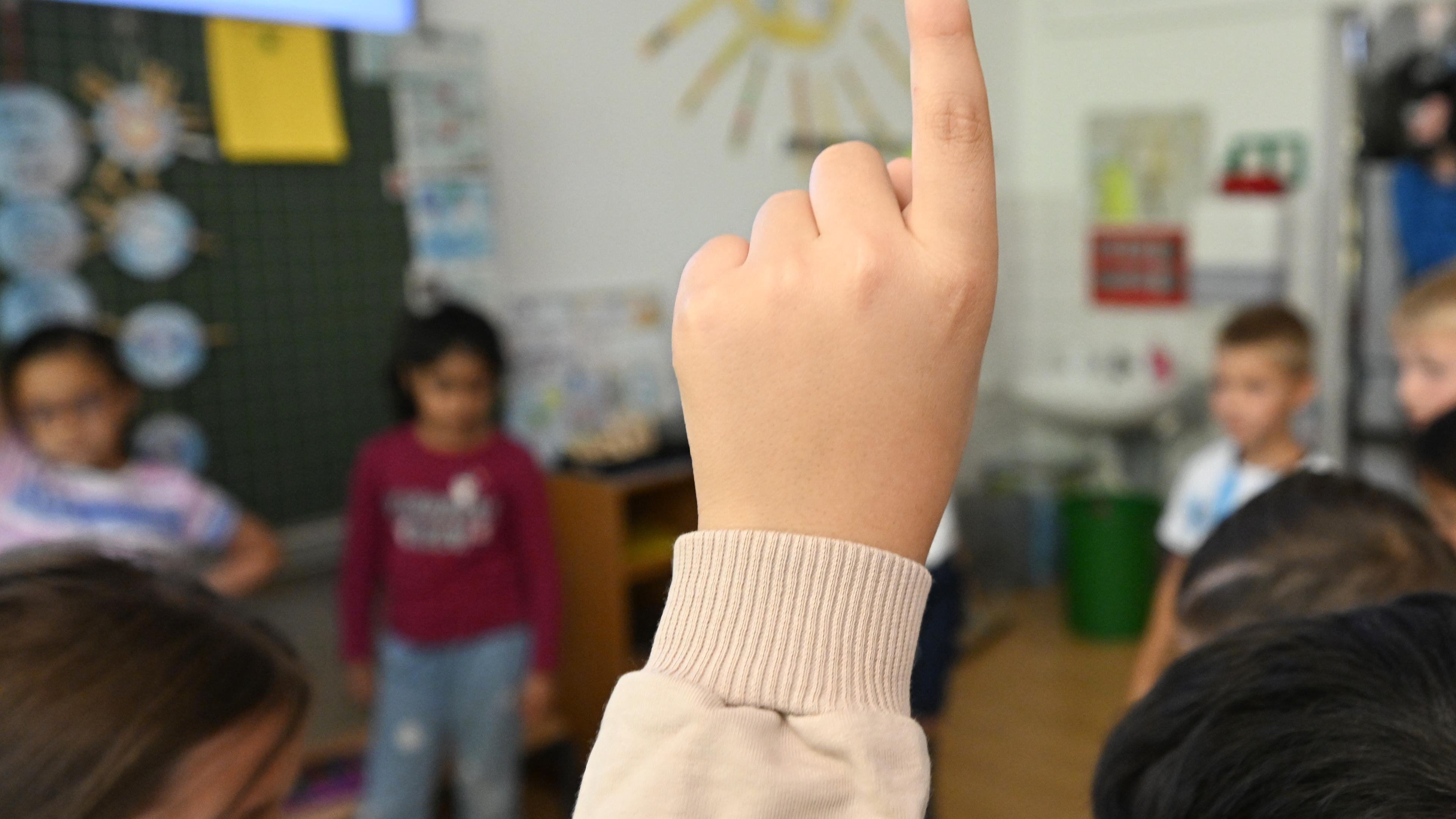 Baden-Württemberg, Stuttgart: Schüler einer Grundschule melden sich bei einer Schulstunde.