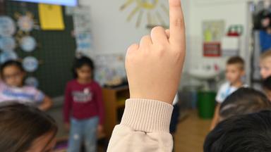 Baden-Württemberg, Stuttgart: Schüler einer Grundschule melden sich bei einer Schulstunde.