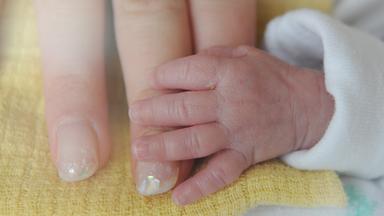 Baby hält die Hand der Mutter