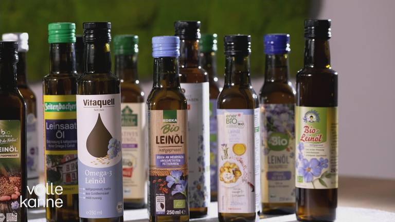 Mehrere Flaschen Leinöl stehen nebeneinander und hintereinander.