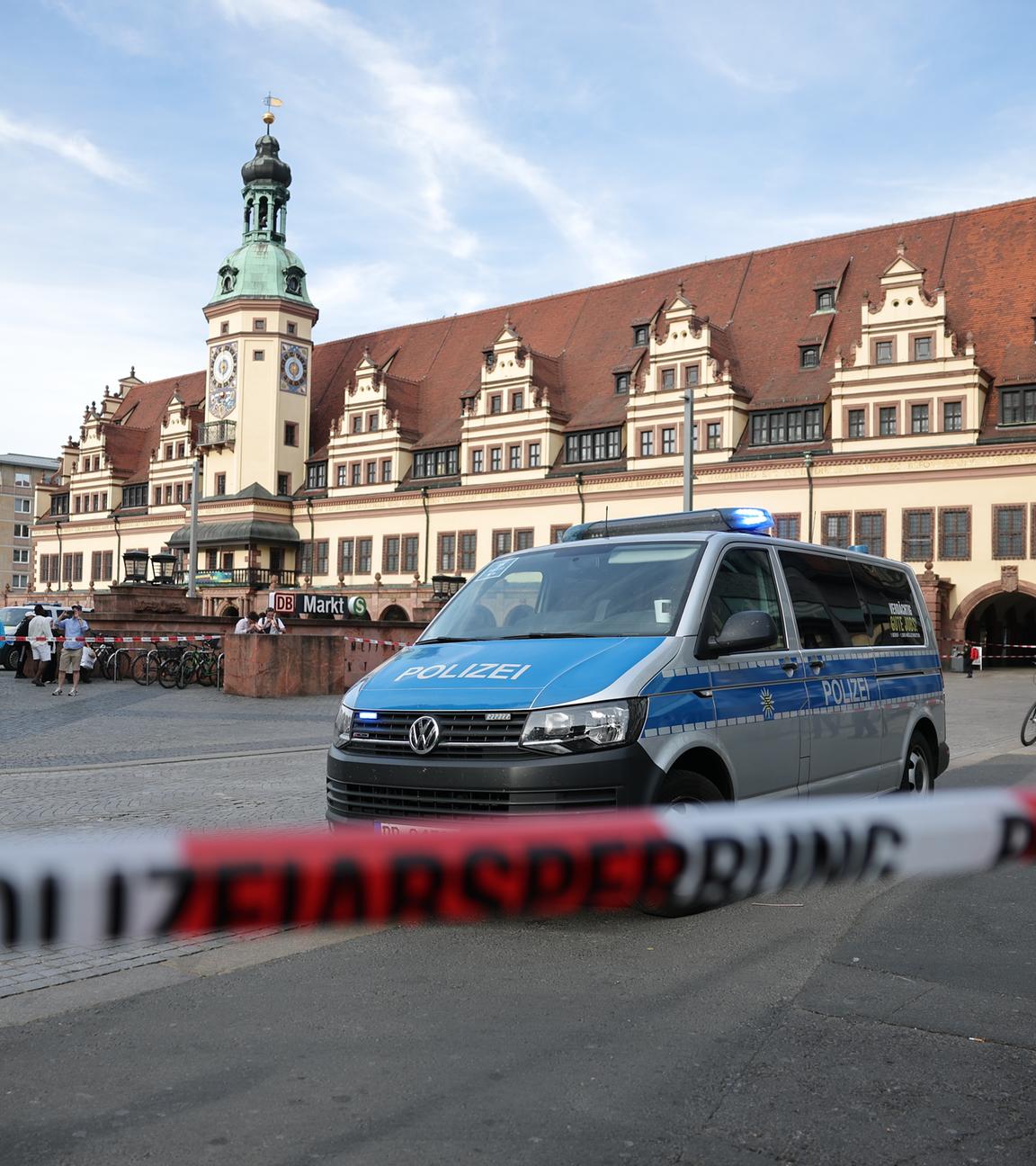 Leipzig: Ein Polizeiwagen parkt hinter einer Polizeiabsperrung an der Stelle, wo ein Auto in eine Menschengruppe gefahren ist