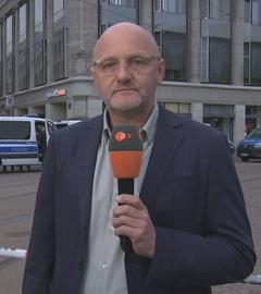 Thomas Bärsch in der Leipziger Fußgängerzone. Im Hintergrund stehen Polizeiwägen.