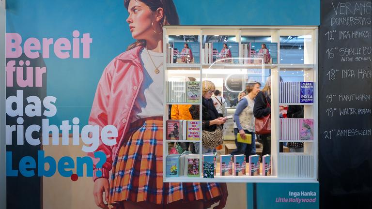 Besucher sind durch ein Schaufenster eines Standes auf der Leipziger Buchmesse zu sehen