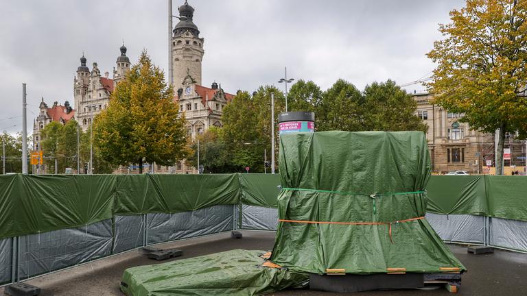 Der mit grünen Planen verhüllte Grundstein für das Freiheits- und Einheitsdenkmal steht auf dem Wilhelm-Leuschner-Platz. Zum 36. Jahrestag der friedlichen Revolution soll am 9. Oktober auf diesem Platz der Grundstein für das lange geplante Freiheits- und Einheitsdenkmal gelegt werden. Für rund fünf Millionen Euro soll ein dezentrales Denkmal aus 50 weißen Skulpturen entstehen.