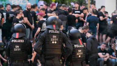 Einsatzkräfte der Polizei bewachen eine Gruppe Fußballfans in der Innenstadt.