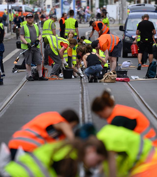 Leipzig: Freiwillige Helferinnen und Helfer befreien im Zentrum Straßenbahnschienen von verklebter Fugenmasse