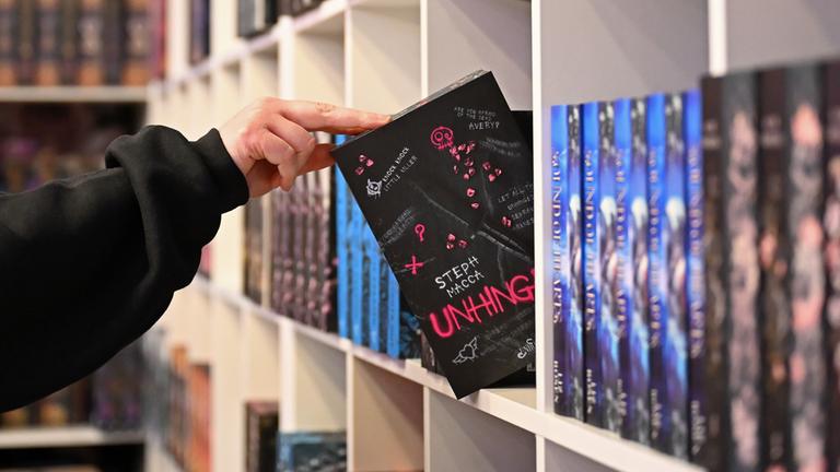 Eine Mitarbeiterin räumt ein Regal am Stand des Verlages Buchmädchen auf der Leipziger Buchmesse ein.