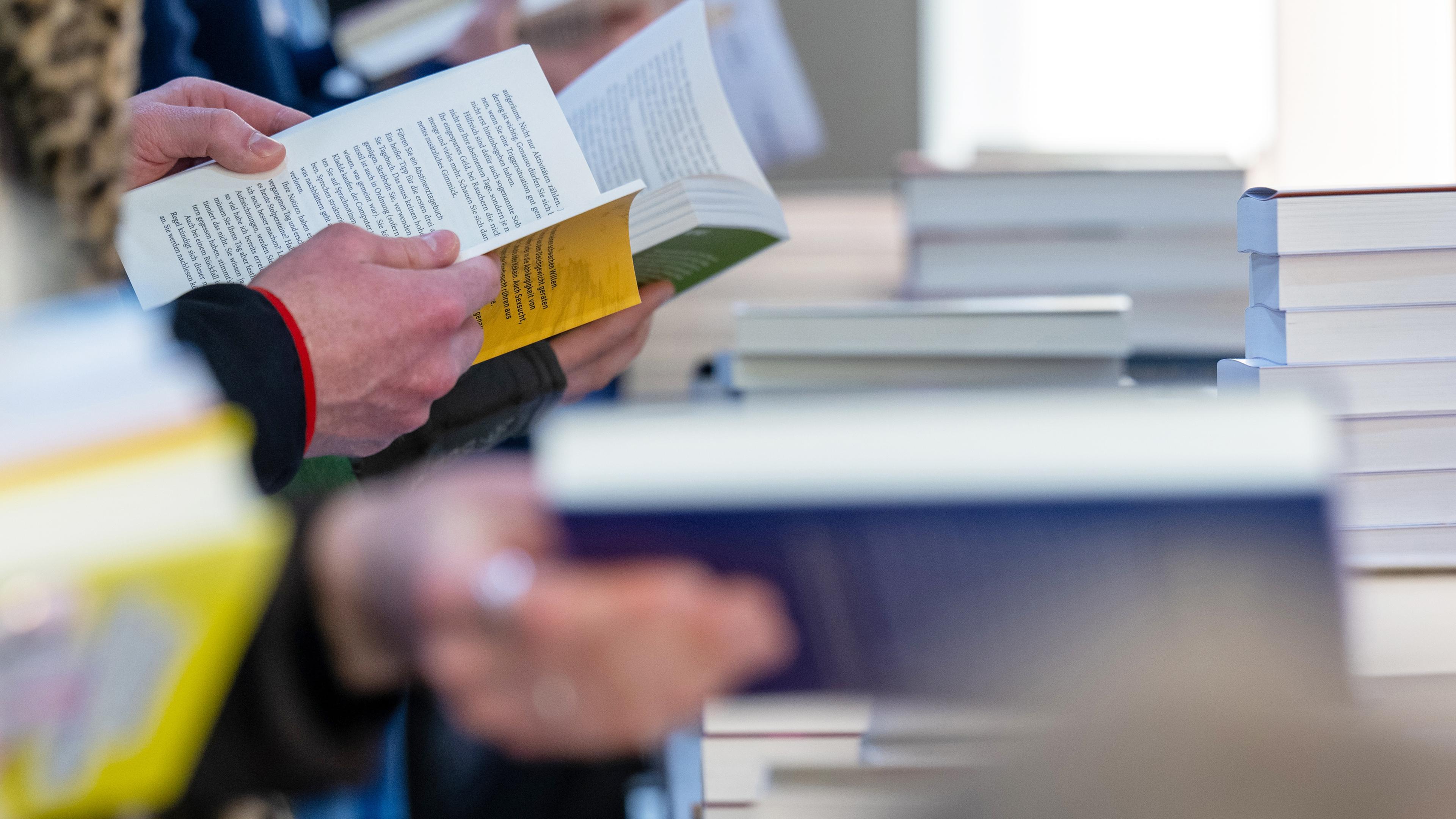 Besucher der Leipziger Buchmesse lesen am Stand von Random House. (recrop) Auf dem Frühjahrstreffen der Buchbranche präsentieren sich über 2000 Aussteller aus 40 Ländern mit ihren Neuheiten.