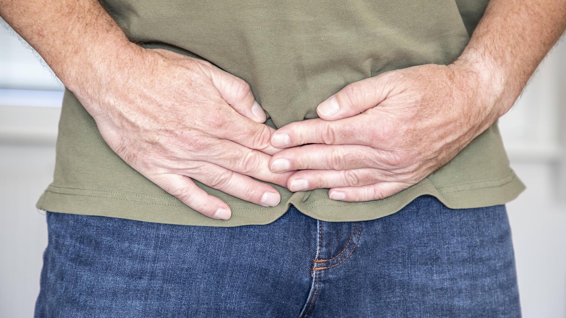Leistenbruch? Ein Mann hält sich die Hände vor den Bauch
