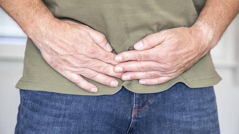 Mann hält sich die Hände vor den Bauch