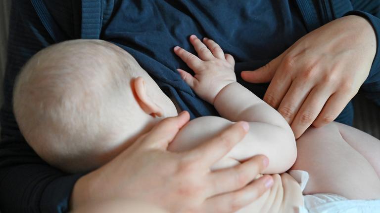 Sachsen, Leipzig: Eine Mutter stillt ihr Baby in einem ruhigen Moment zu Hause.
