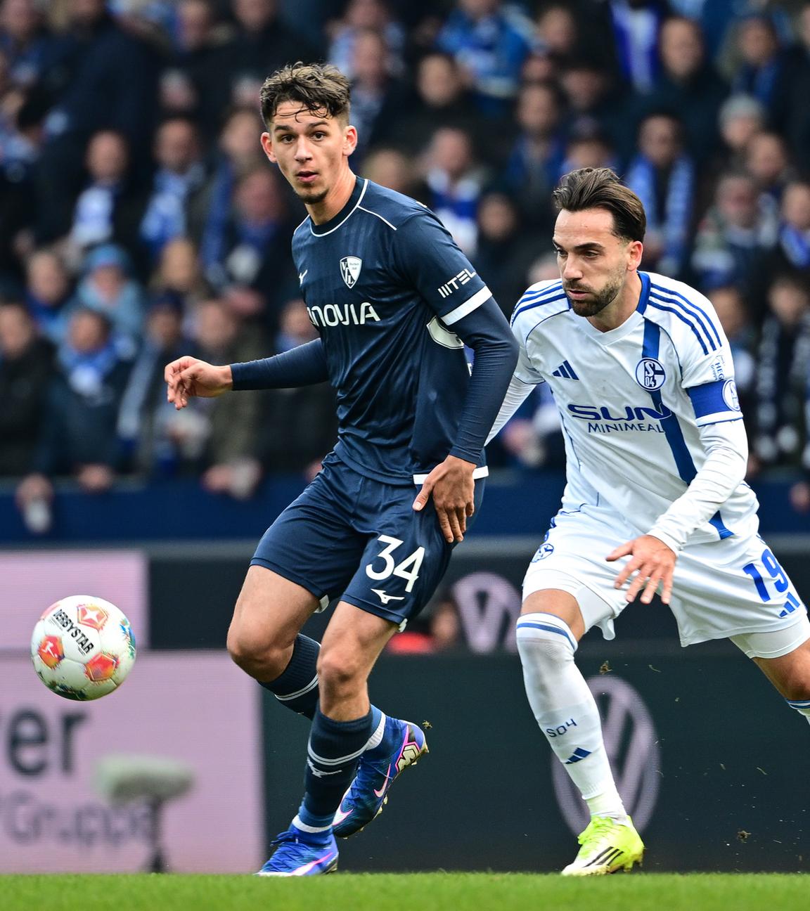 In der Zweitligapartie des VfL Bochum gegen den FC Schalke 04 wird der Ballführende Bochumer Cajetan Lenz von Schalker Kenan Karaman von hinten bedrängt 