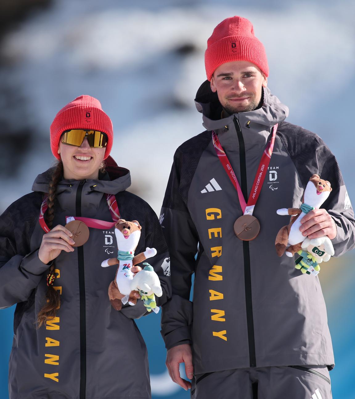 Die deutsche Biathletin und Skilangläuferin Leonie Maria Walter präsentiert freudig mit ihrem Coach Christian Krasman ihre Bronzemedaille