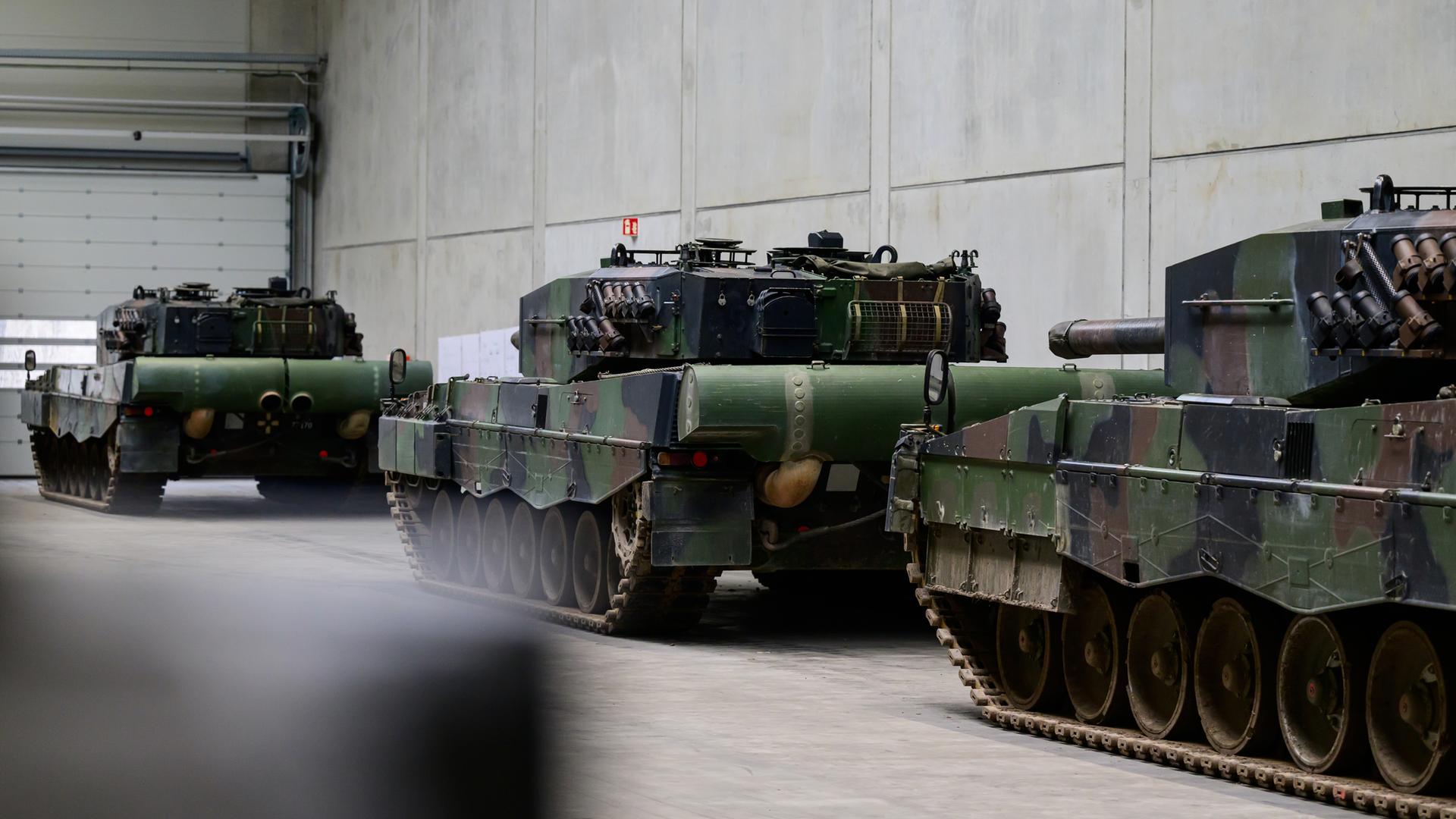 Mehrere Leopard-Kampfpanzer stehen in einer Halle von Rheinmetall.