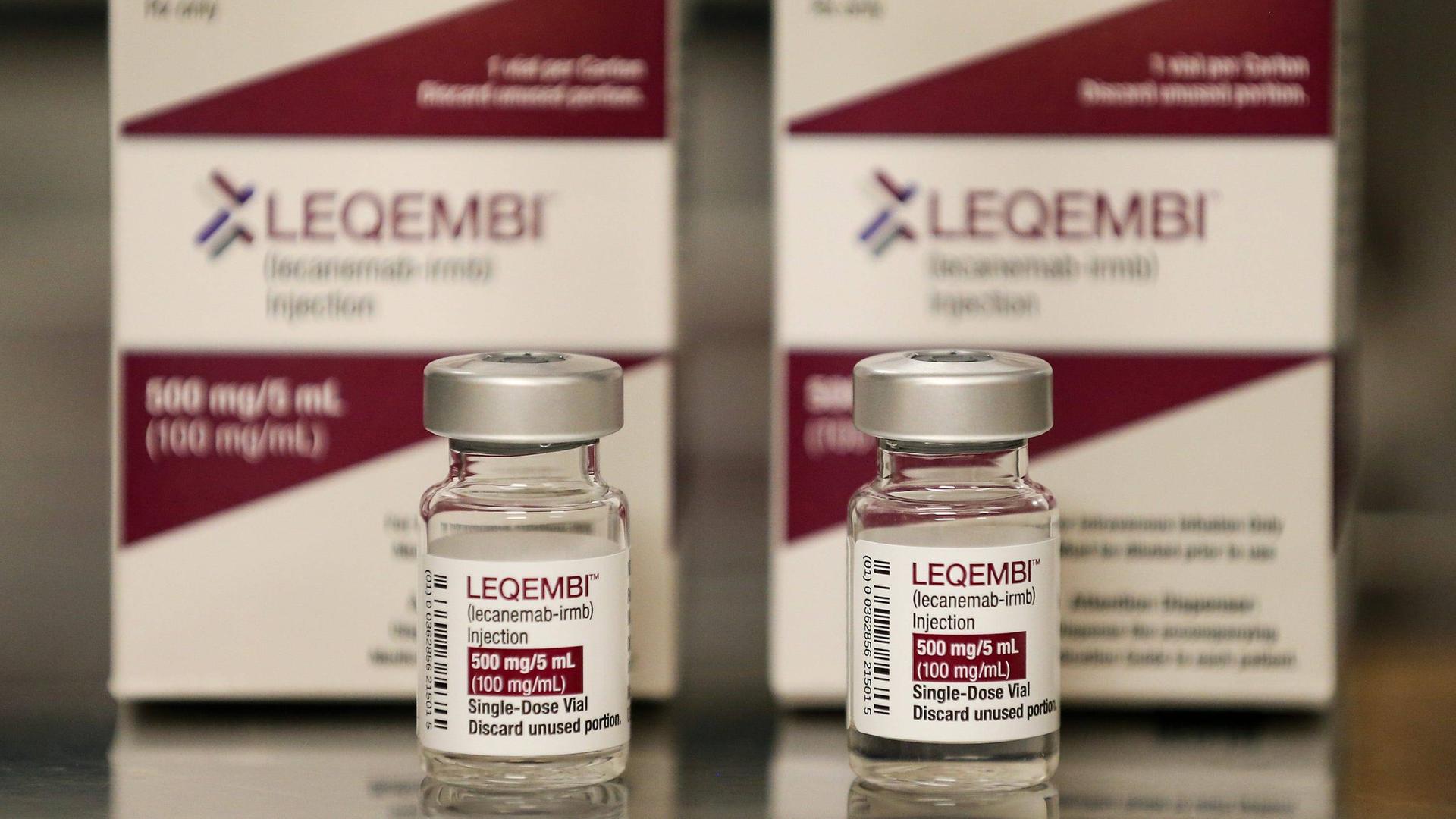 Zwei Packungen des Medikaments Leqembi mit zwei Ampullen davor.