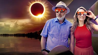 Harald Lesch und Jasmina Neudecker mit Sonnenfinsternisbrillen vor verdeckter Sonne