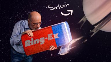 Harald Lesch mit einem riesigen Radiergummi neben Saturnringen