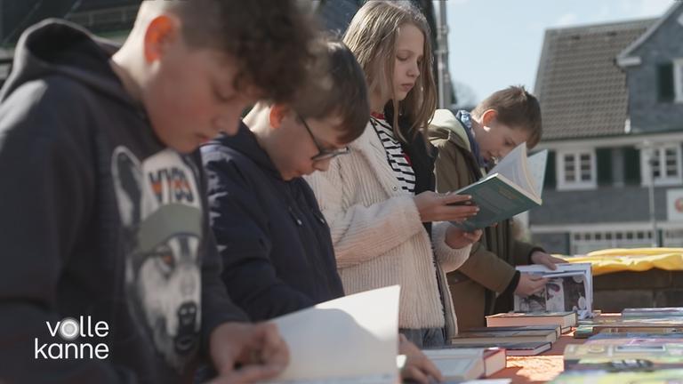 Schüler und eine Schülerin schauen sich Bücher an