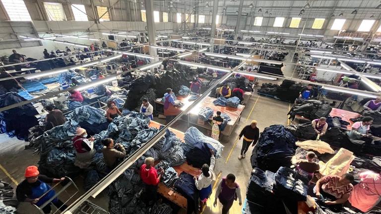 Eine Textilfabrik, in der Jeans hergestellt werden. Die Ansicht zeigt das Alltagsgeschehen in der Fabrik von oben.