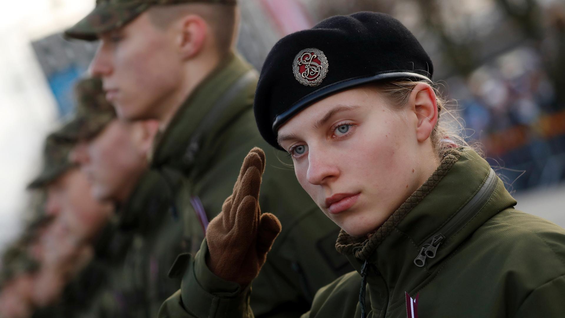 Es ist eine salutierende Frau des lettischen Militärs zu sehen.