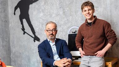Das Bild zeigt Jan Fleischhauer und Levi Penell in einem Raum mit grauer Betonwand, der wie ein Kinder- oder Jugendzimmer inszeniert ist. Links im Bild steht ein niedriges Bett mit gelber Bettwäsche und bunten Motiven, darauf liegt ein kleines rotes Kuscheltier. An der Wand darüber ist die schwarze Silhouette eines Skateboarders zu sehen.