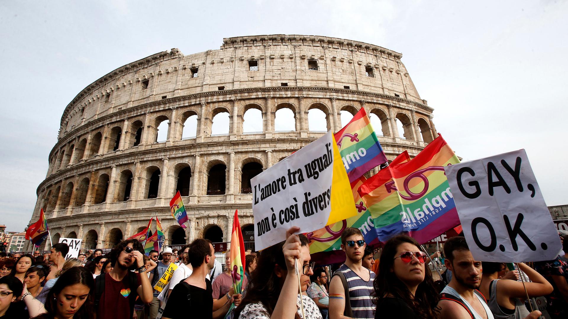 Vor dem Kolloseum demonstrieren Menschen mit Regenbogenflaggen.
